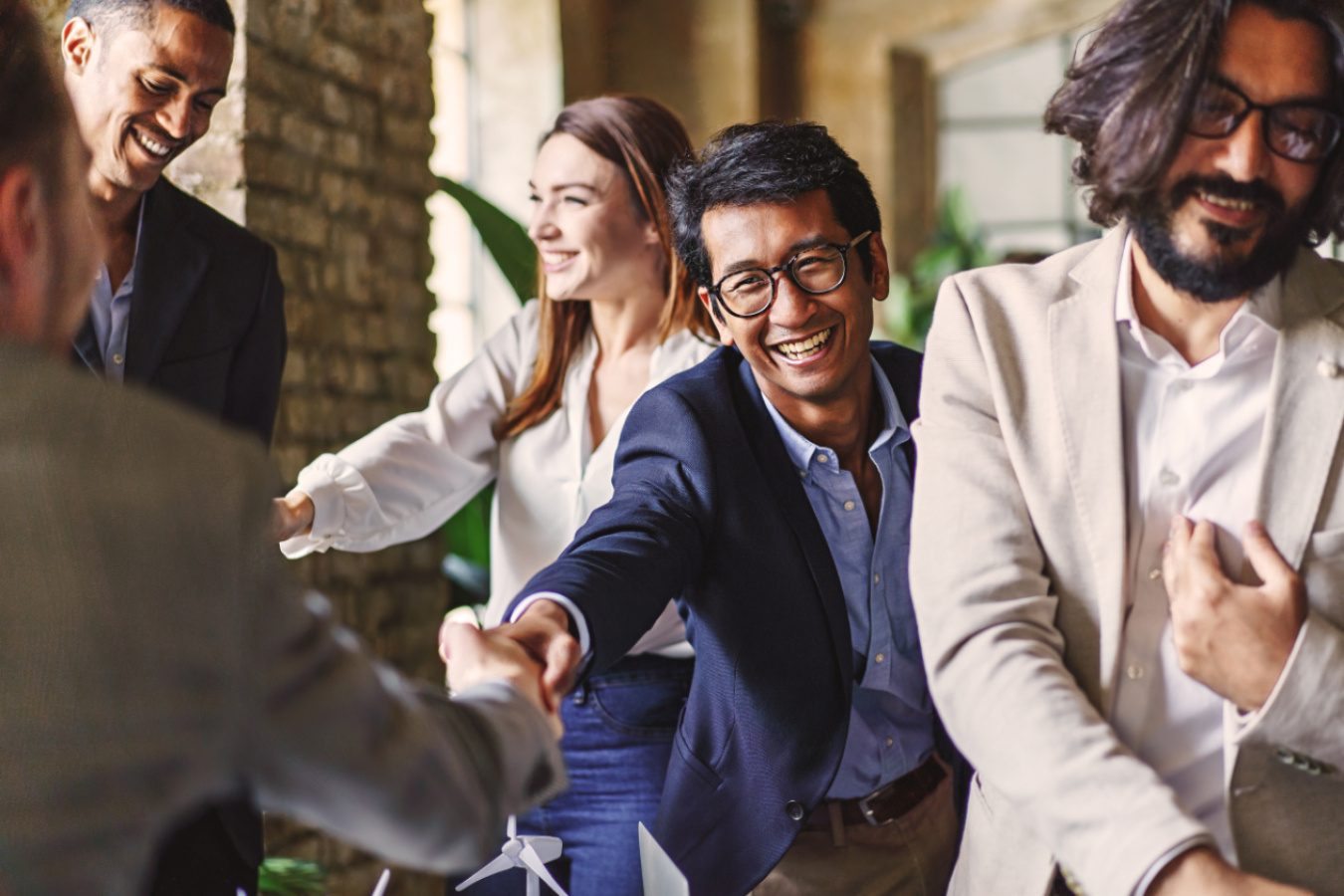 A group of people shake hands and smile after a successful meeting.