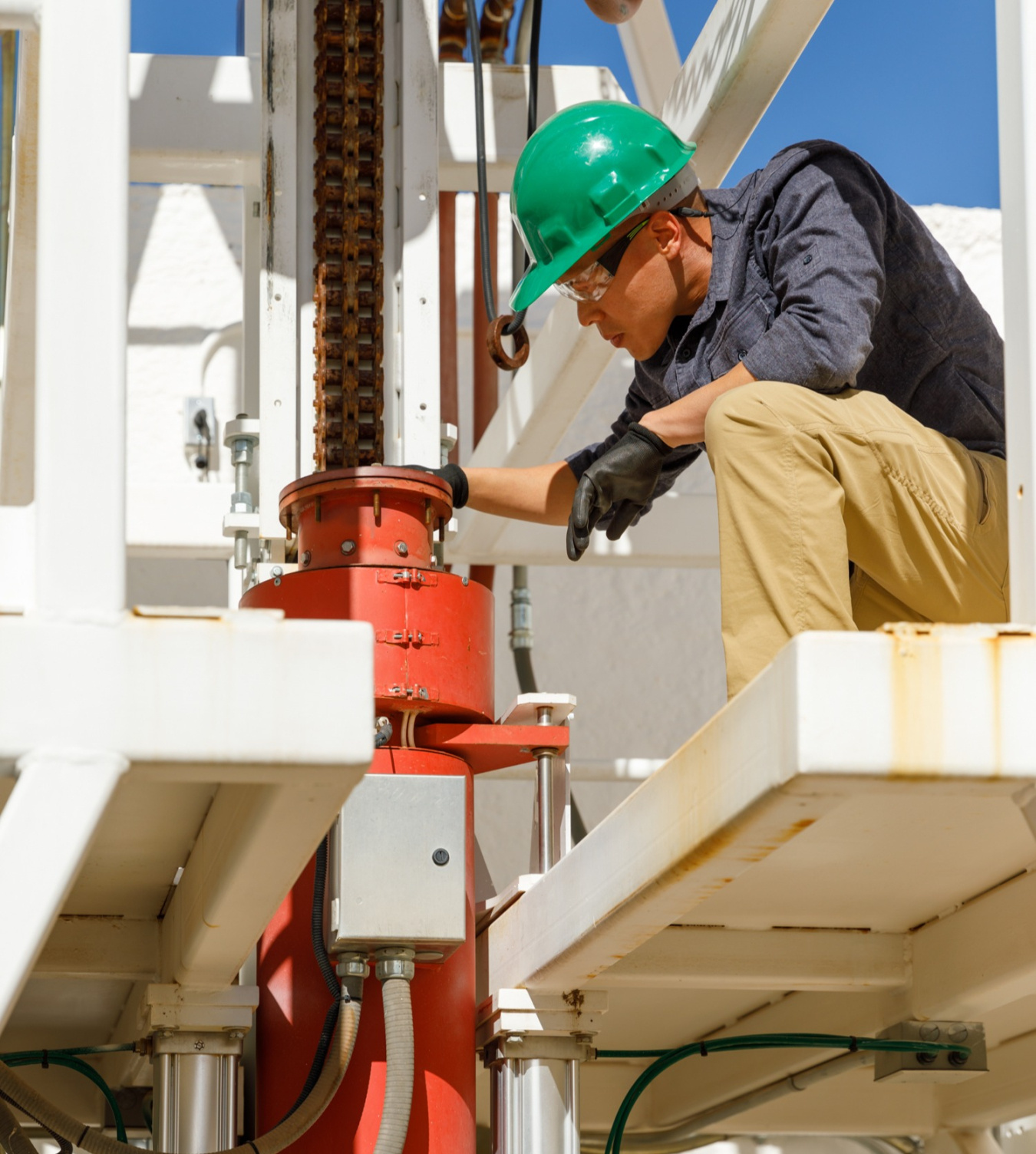 An engineer closely examines drilling equipment at the Sandia National Labs' High Temperature Testing Facility