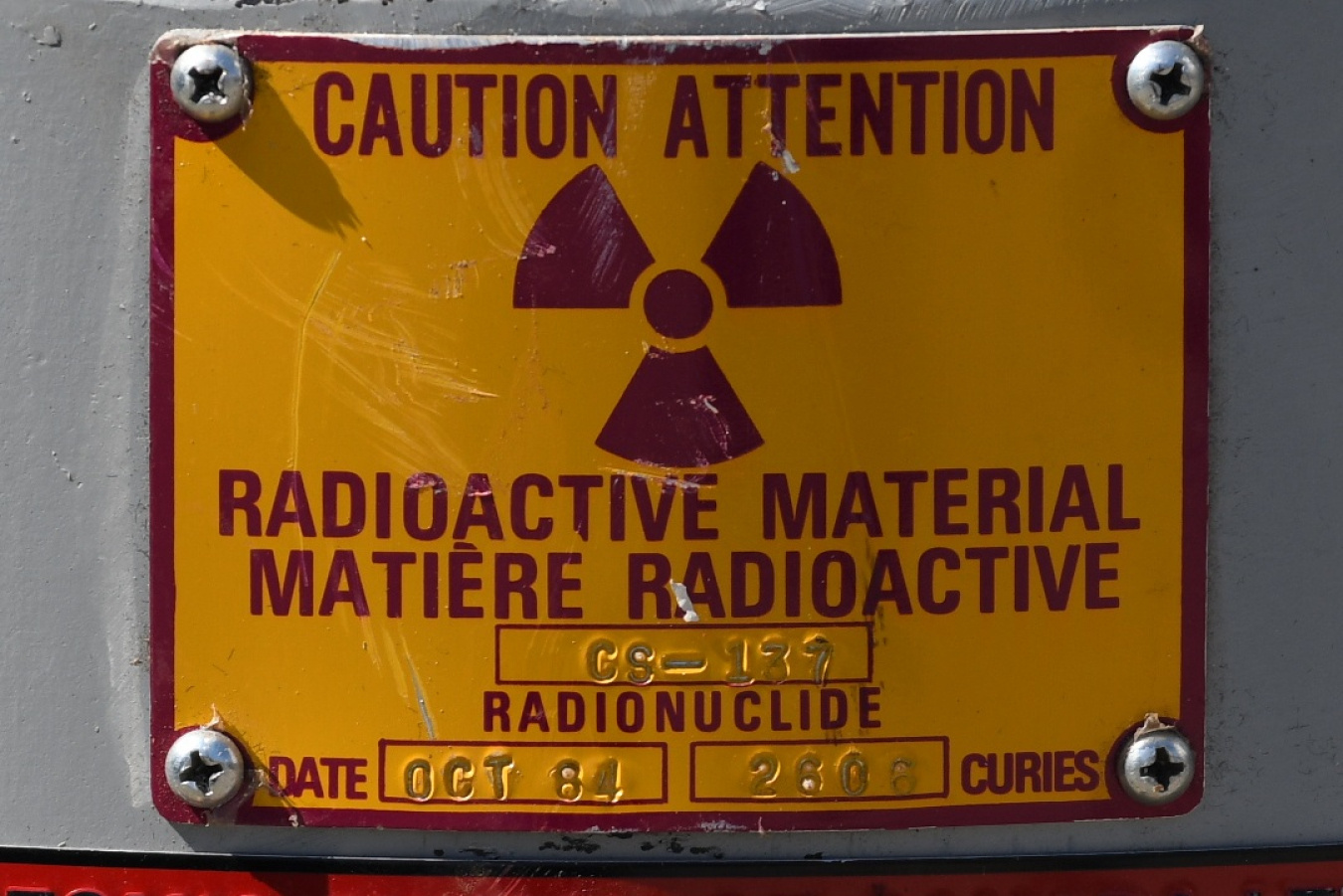 A warning label on the side of a cesium irradiator. It says Caution Radioactive Material in English and French.