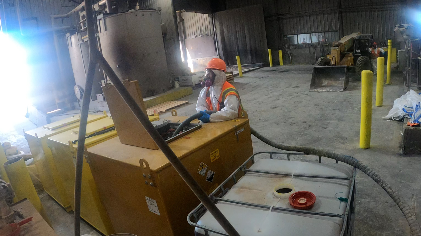 Security camera view of an employee in protective gear working on a waste transfer