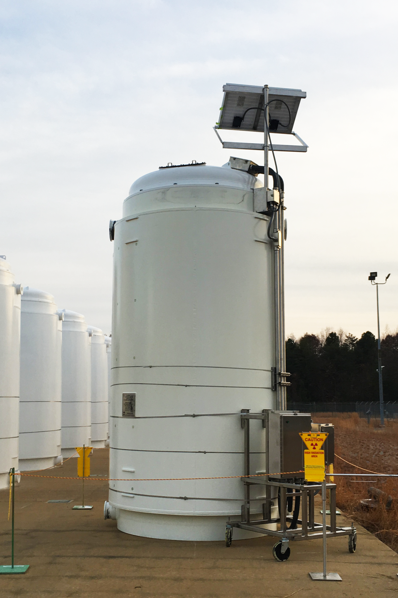 The High Burnup Research Cask, a tall white cylinder with metallic instruments attached to the right side.