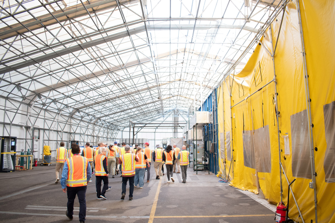 A group of people in orange and yellow safety vests taking a tour of Los Alamos 