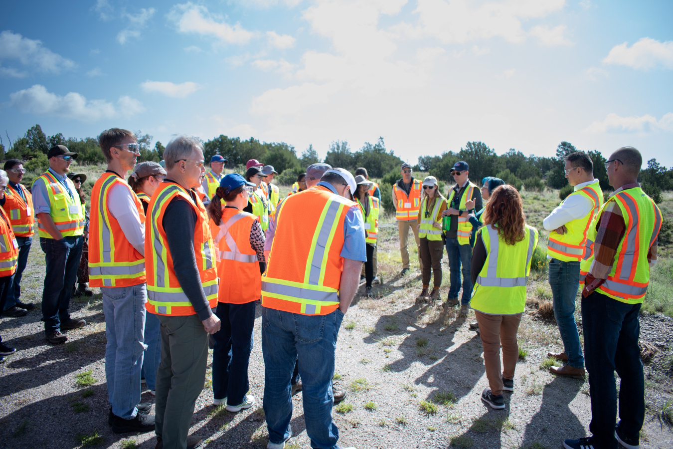 A group of people in yellow and orange safety vests taking a tour of the Los Alamos site