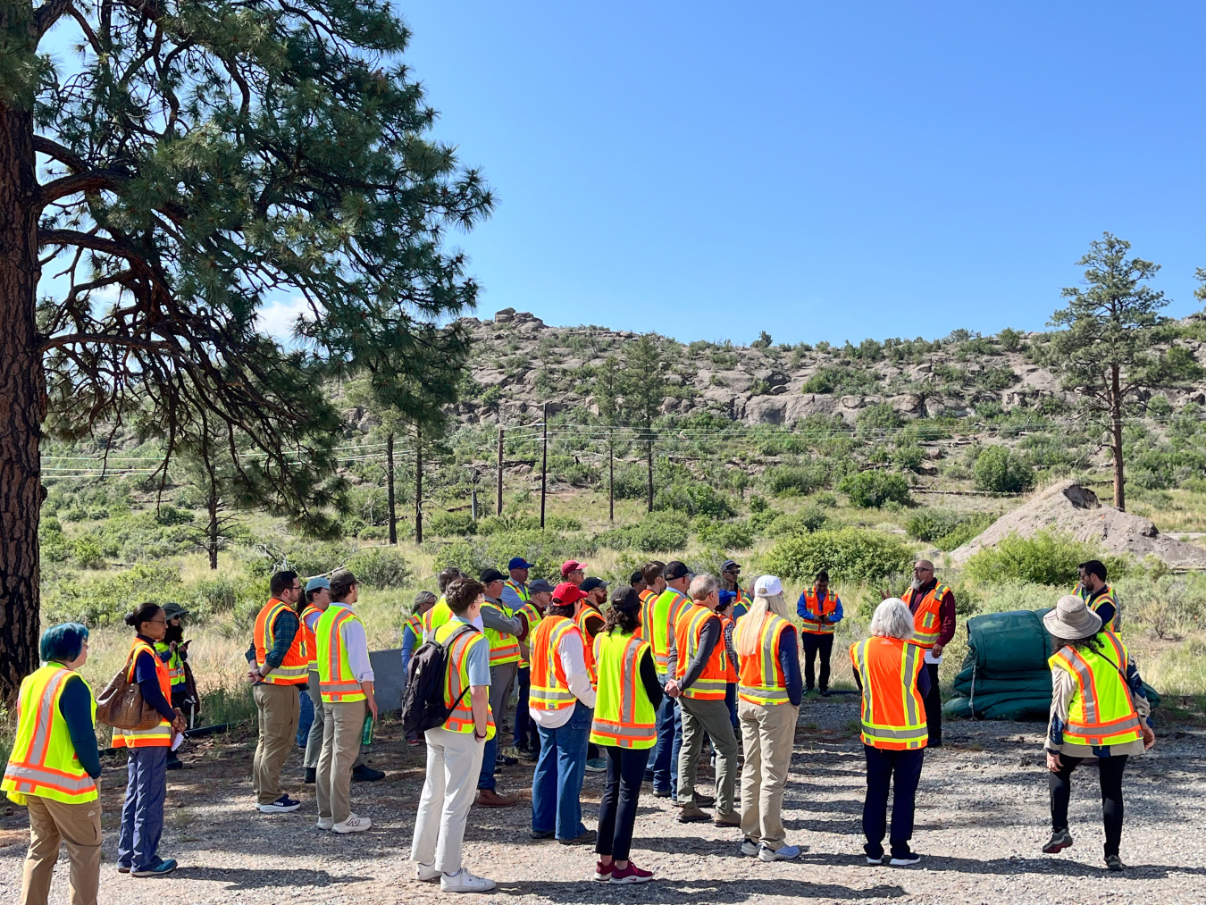 A group of people in orange and yellow safety vests touring Los Alamos