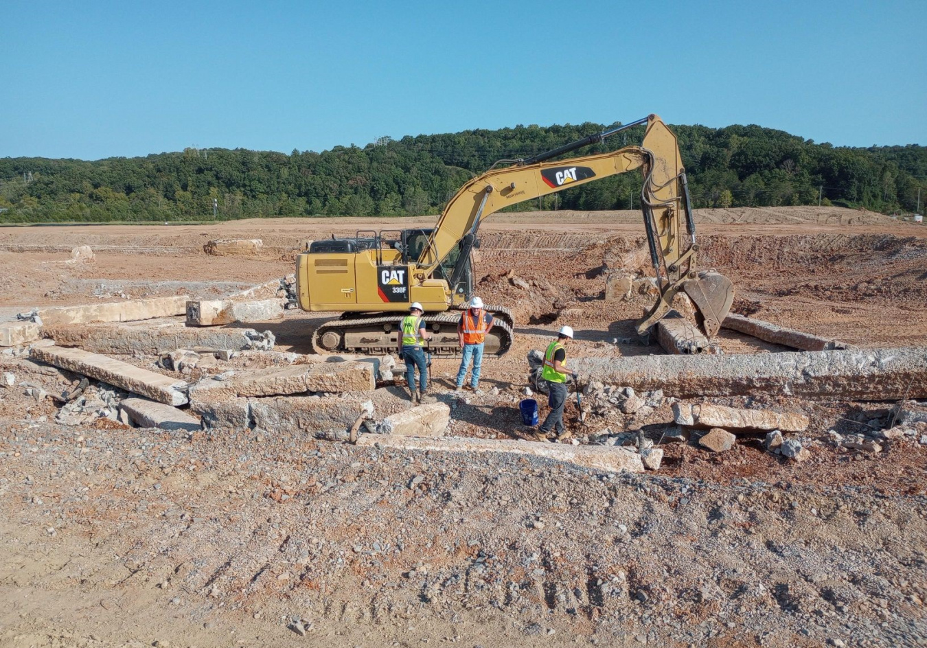 A large yellow excavator working to lay the foundation for a facility building