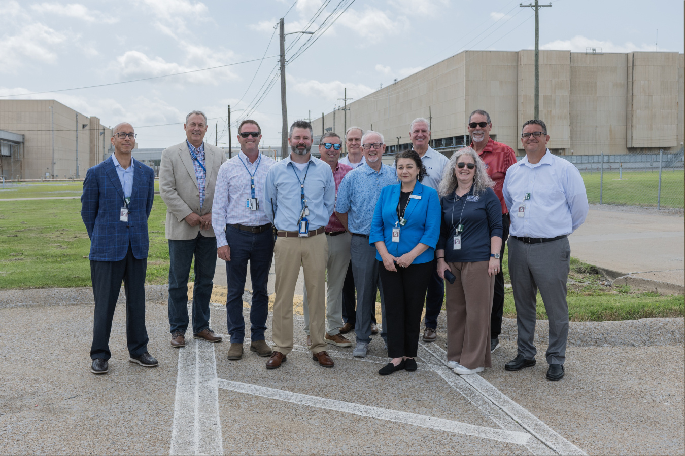 A group of people pose for a group photo outside of facility buildings