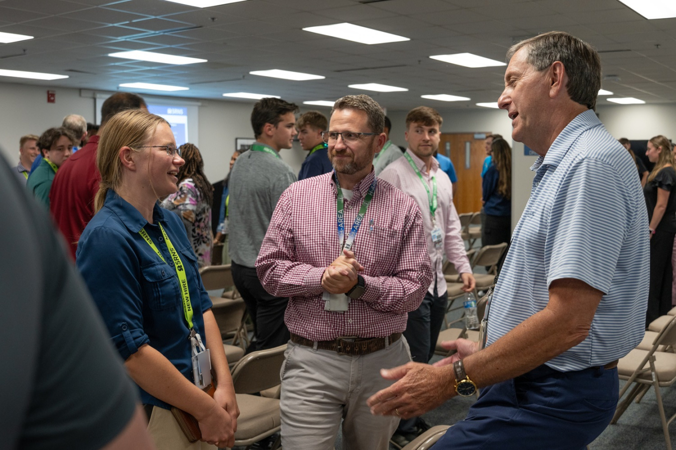 Two employees and an intern speaking to each other at an intern meet and greet event