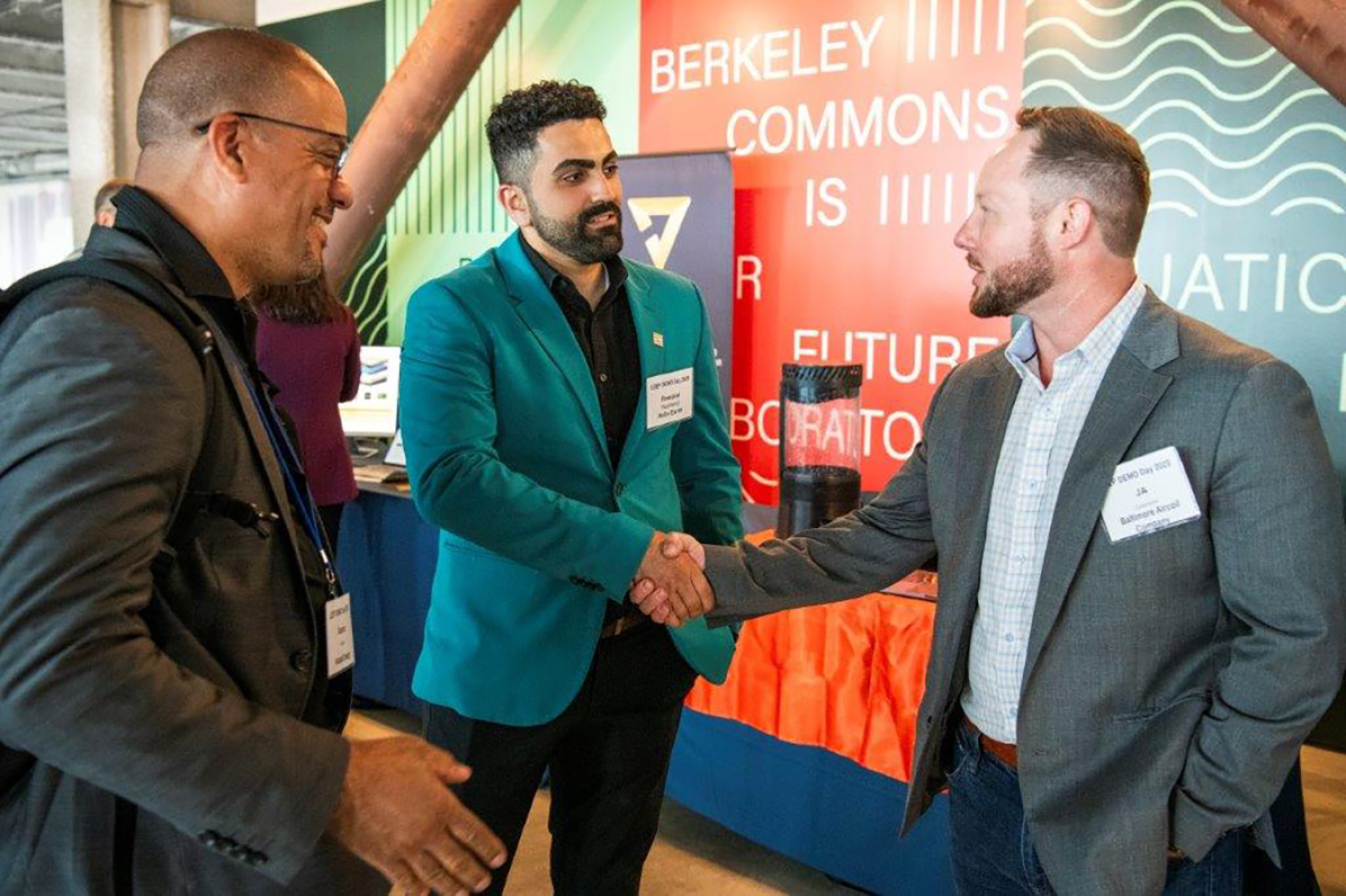 Three men greet one another at event