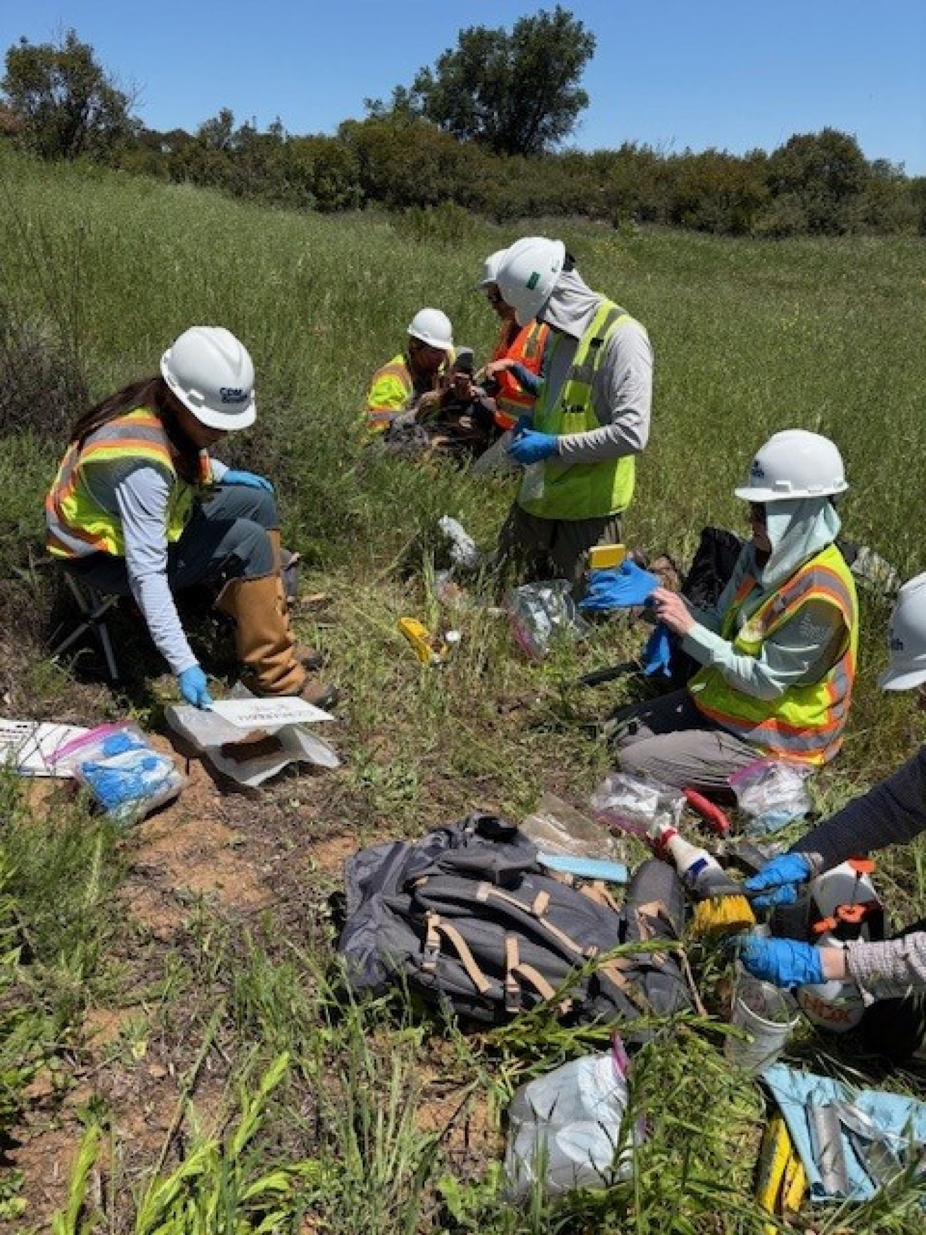 A group of employees in protective gear taking samples of groundwater at the ETEC site