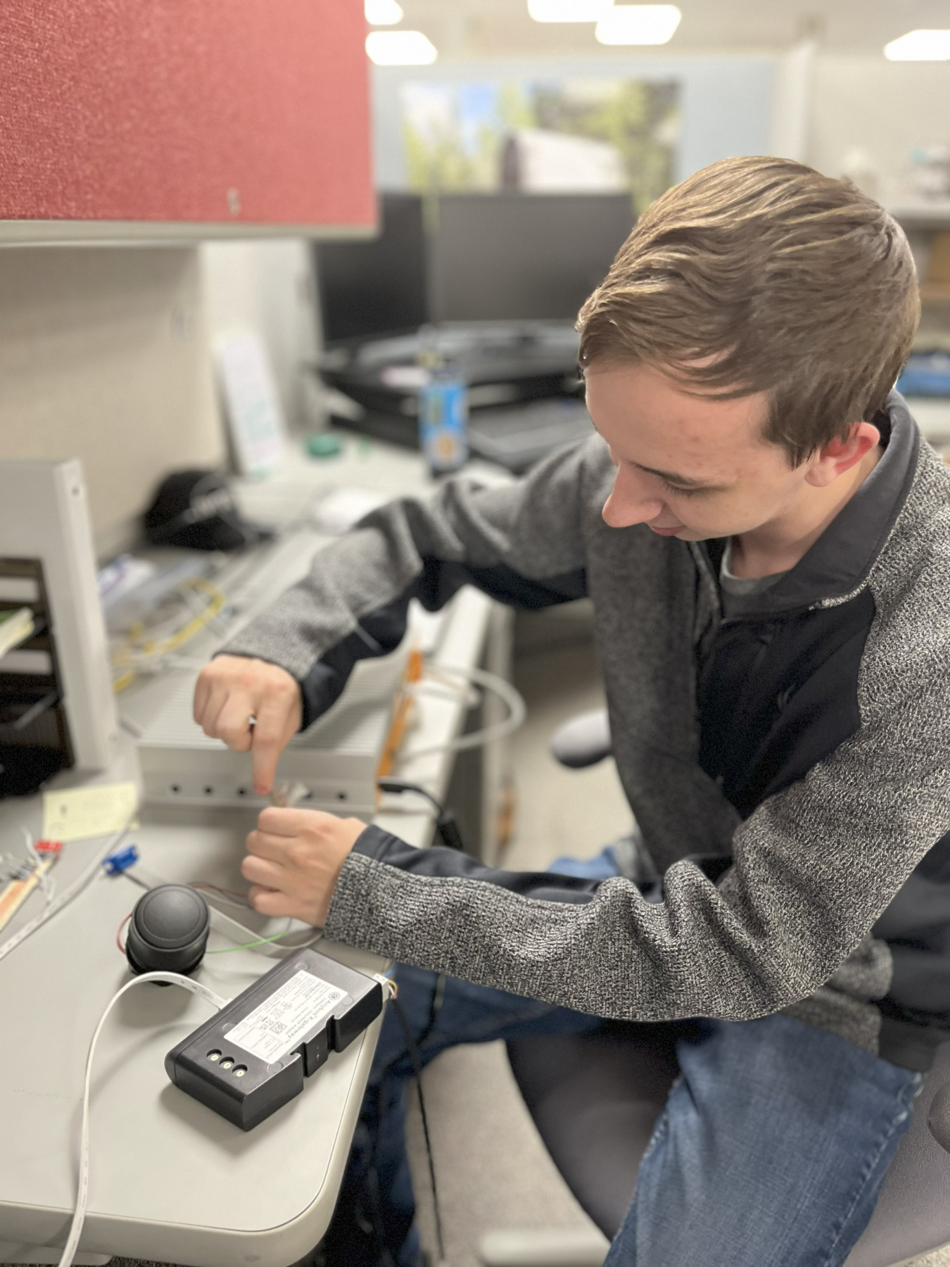 A man working on a machine with wires while sitting at a desk
