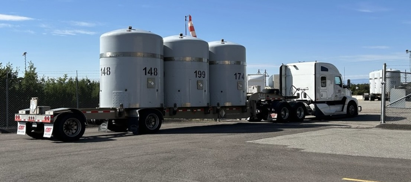 A tractor trailer truck with three large tanks on the back of it
