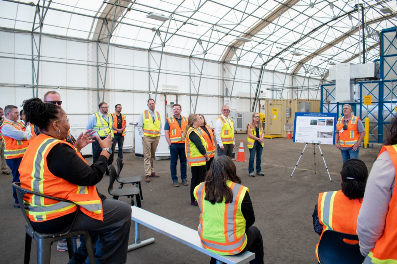 A group of individuals in safety vests listening to a person give a tour