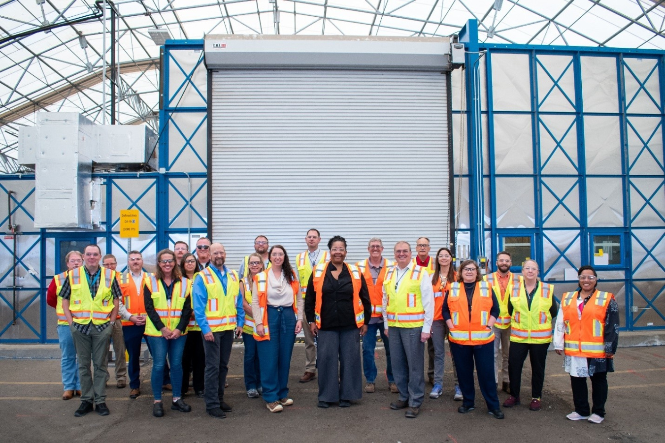 A group of individuals posing for a group picture outside of a facility building