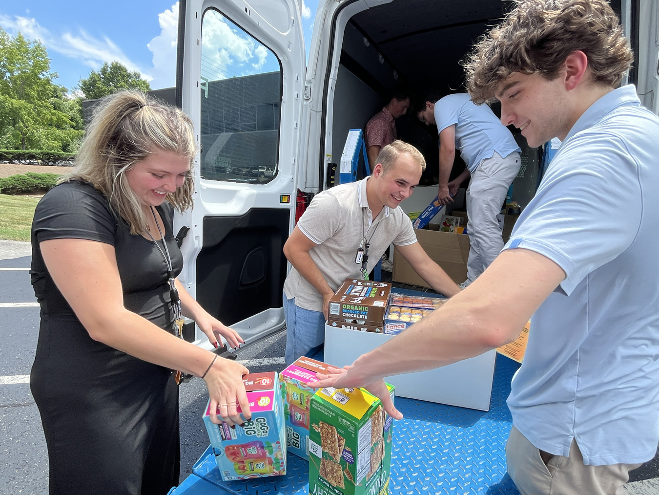 A group of interns taking items out of a van while participating in a food drive