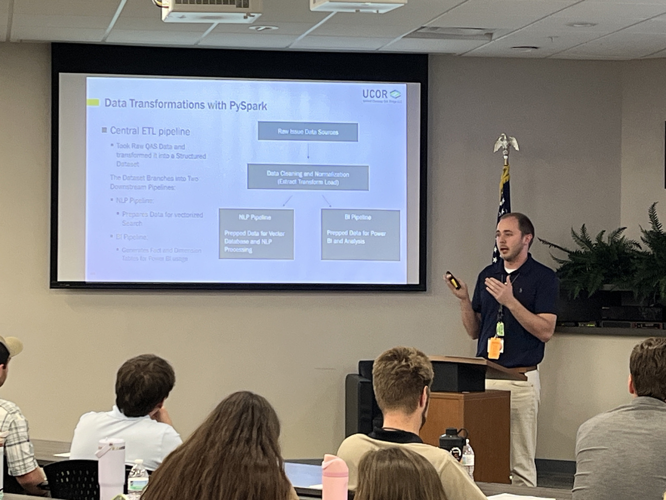 A man giving a presentation with a PowerPoint to a group of people 