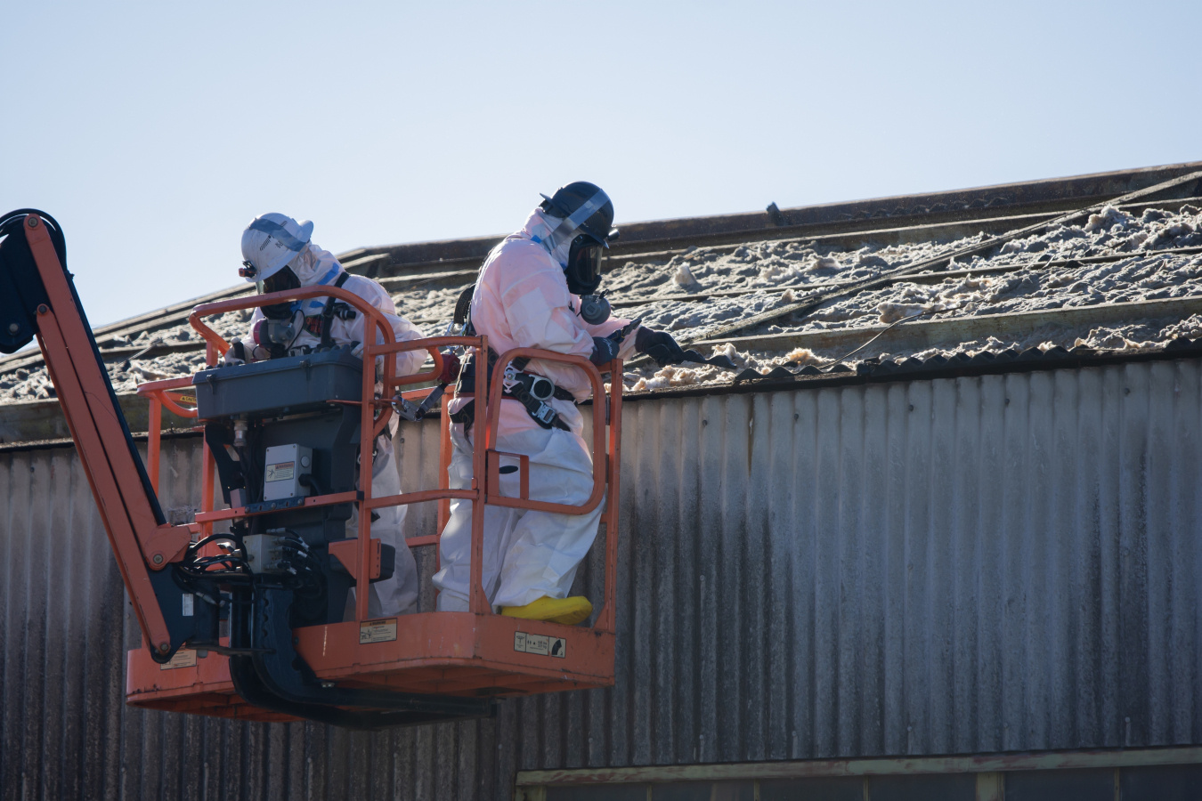 Two employees on a lift crane working on a demolished building