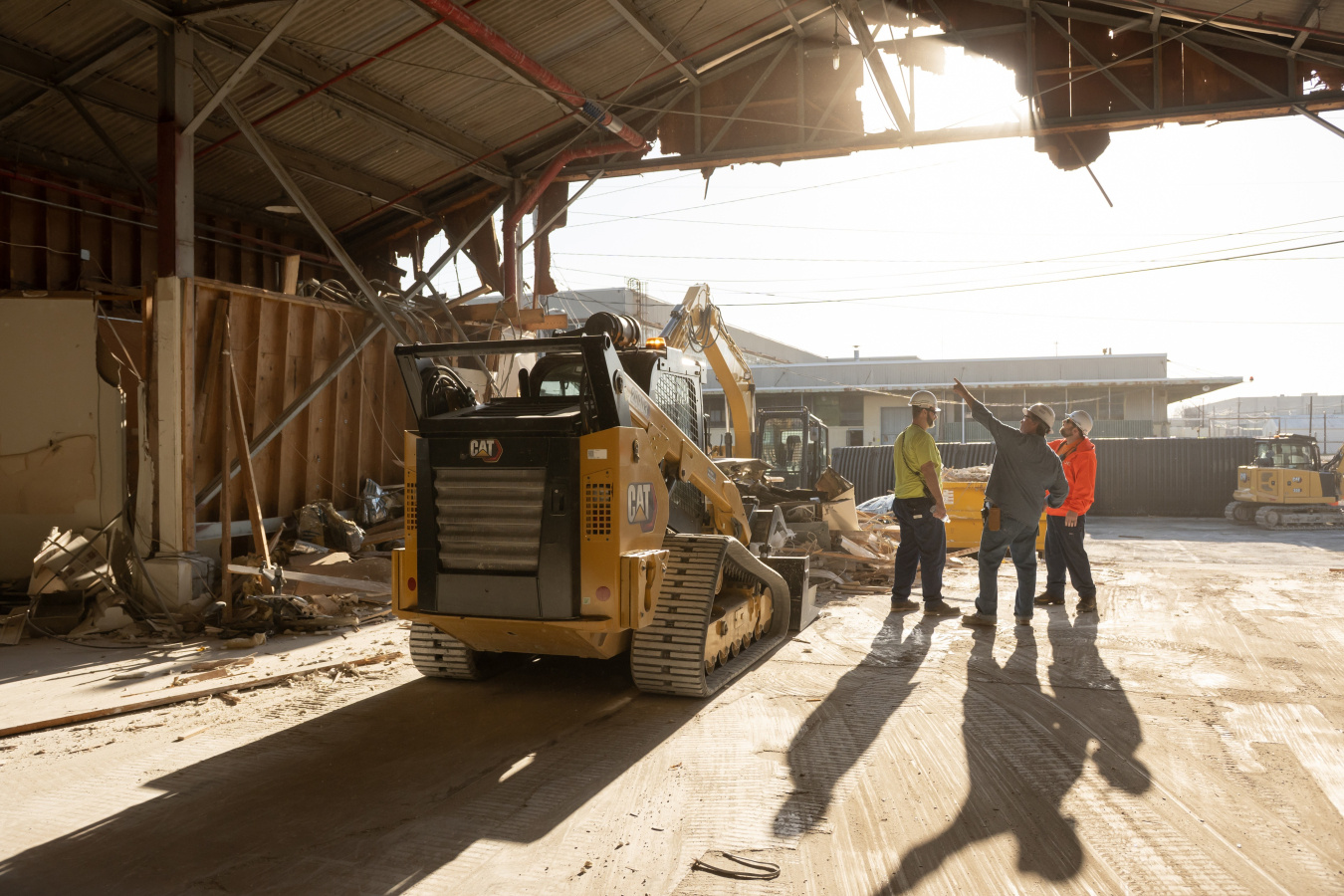 Employees working inside a demolished building with construction vehicles
