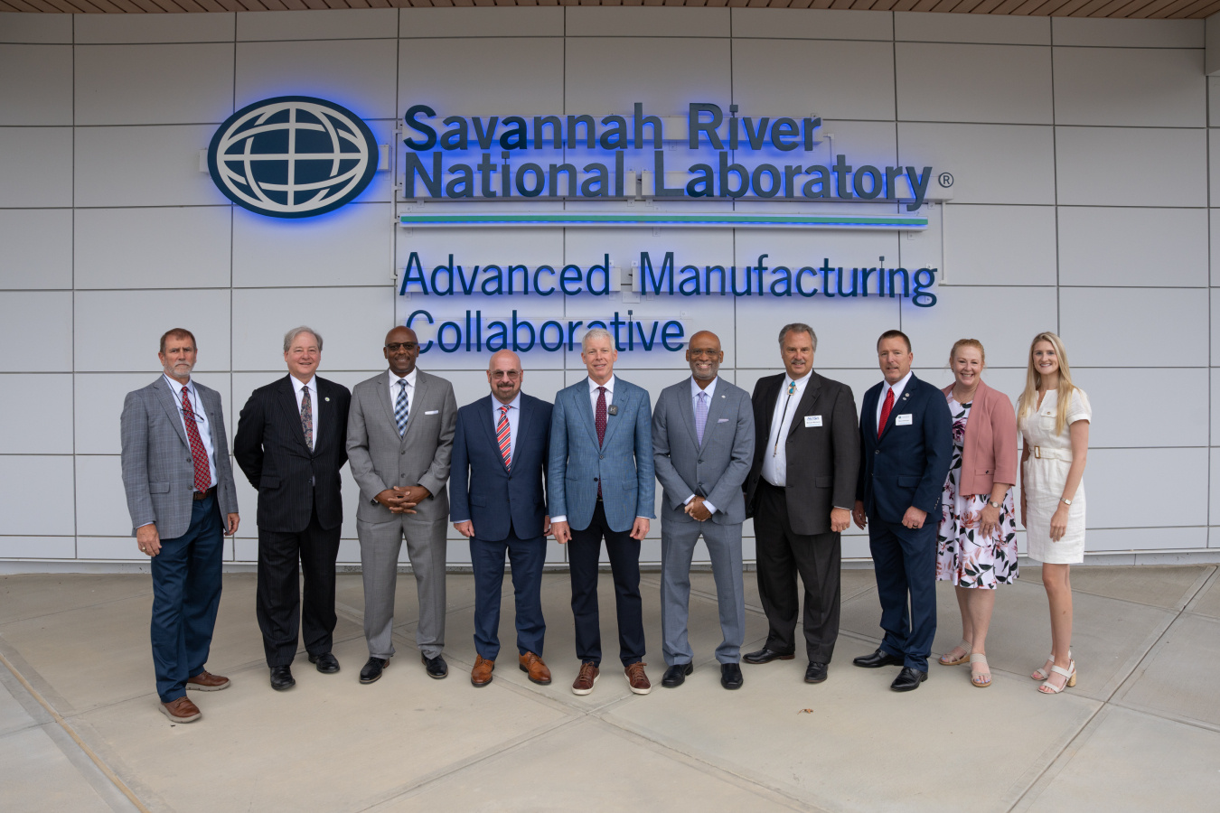 A group of people pose for a photo outside of a new facility center