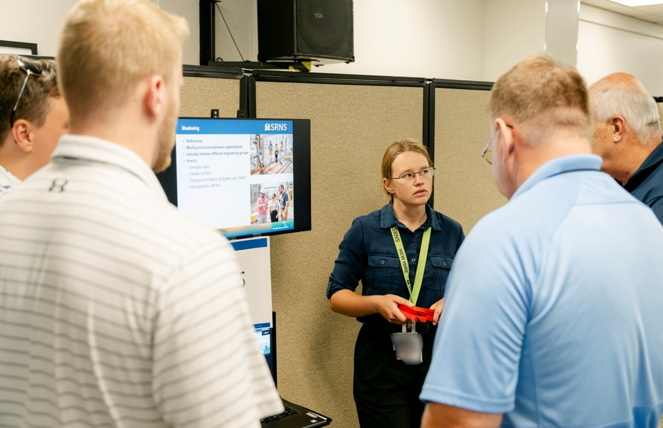 A group of employees listening to an intern give a presentation 