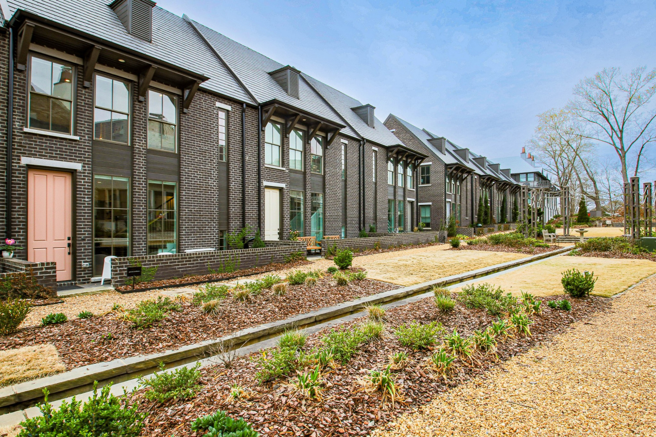 Townhomes with dark bricks and pink and white doors.