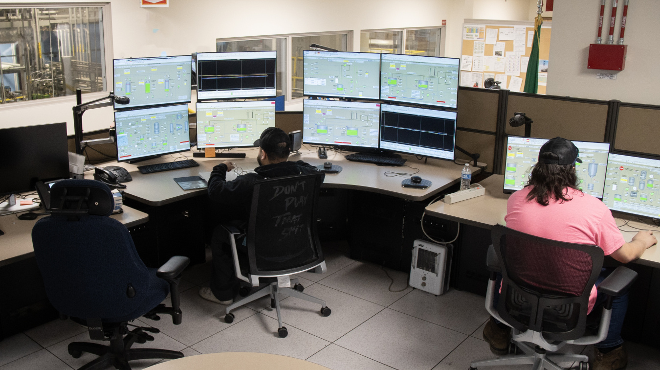 Two employees sitting at tables with monitors and computers