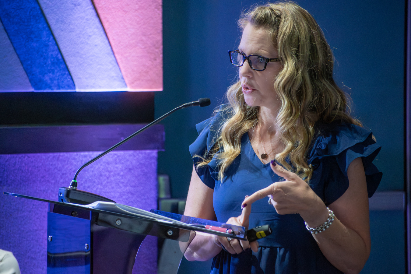 An up close shot of a woman speaking into a microphone on a podium 