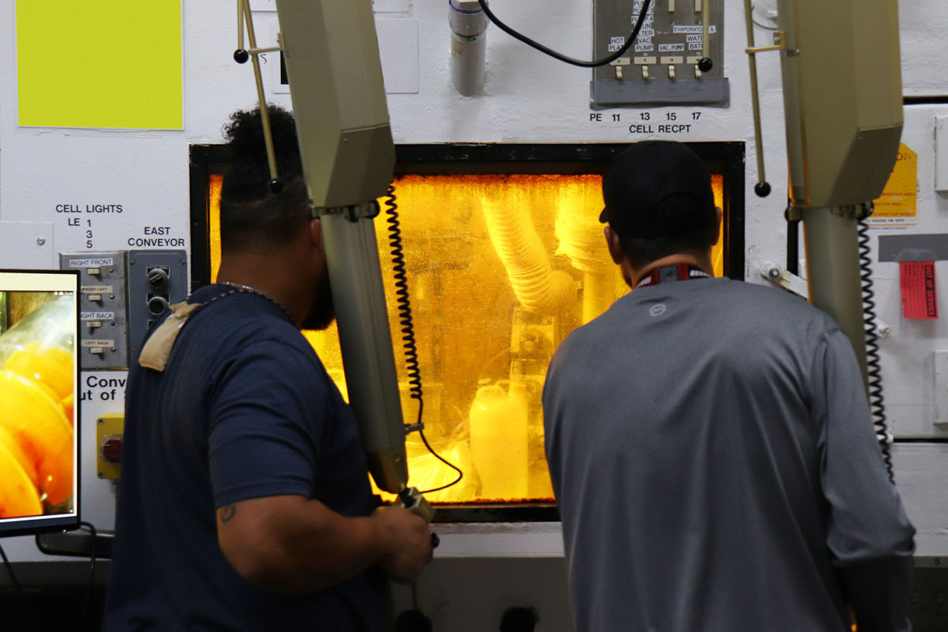 Two employees standing in front of a hot cell box
