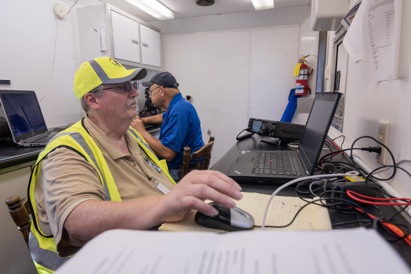 Two men working in an emergency services operations room sitting at desks