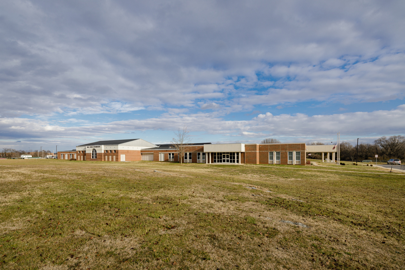 A school building behind lawns of grass.