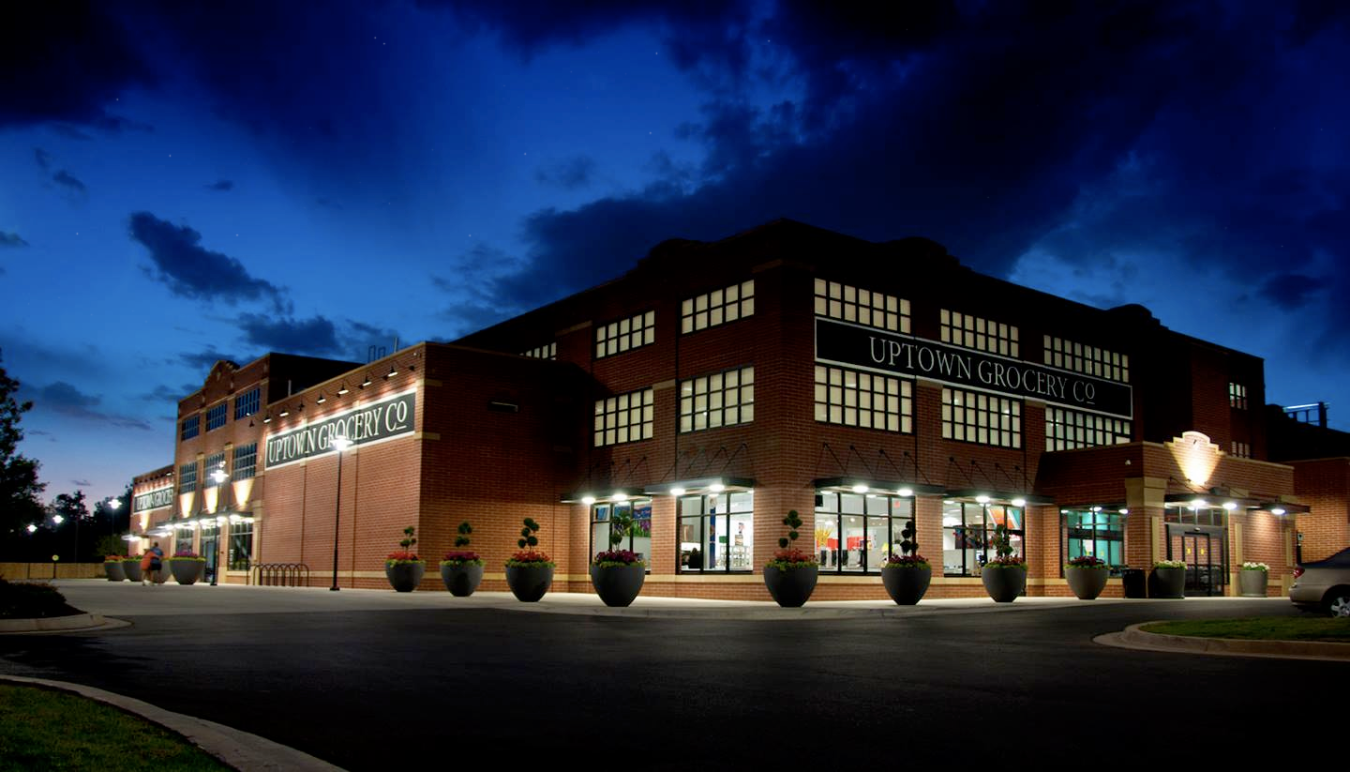 A large brick building with the words “Uptown Grocery Co.” on the side at night.