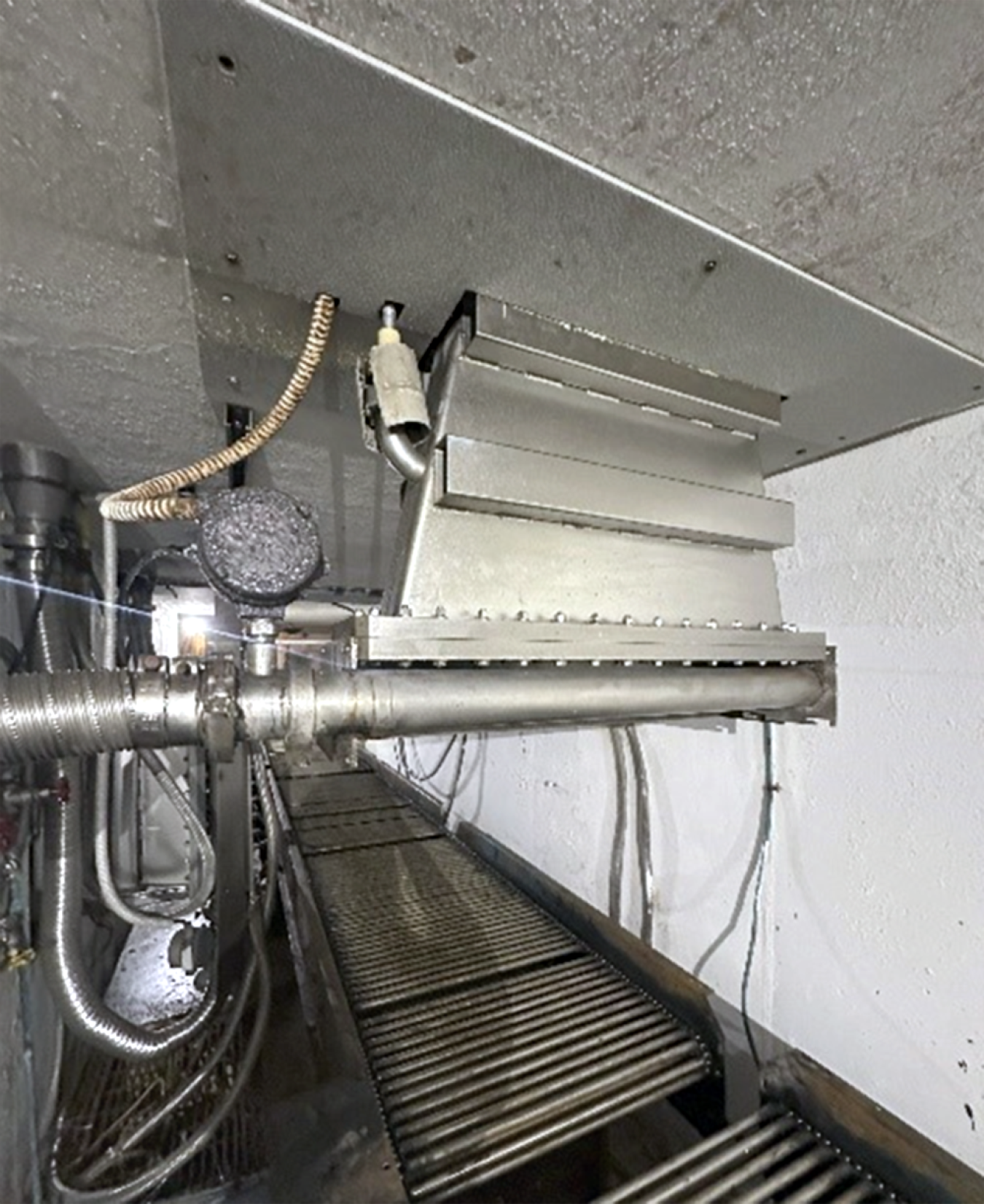 A photo of a metal machine above a conveyor belt.