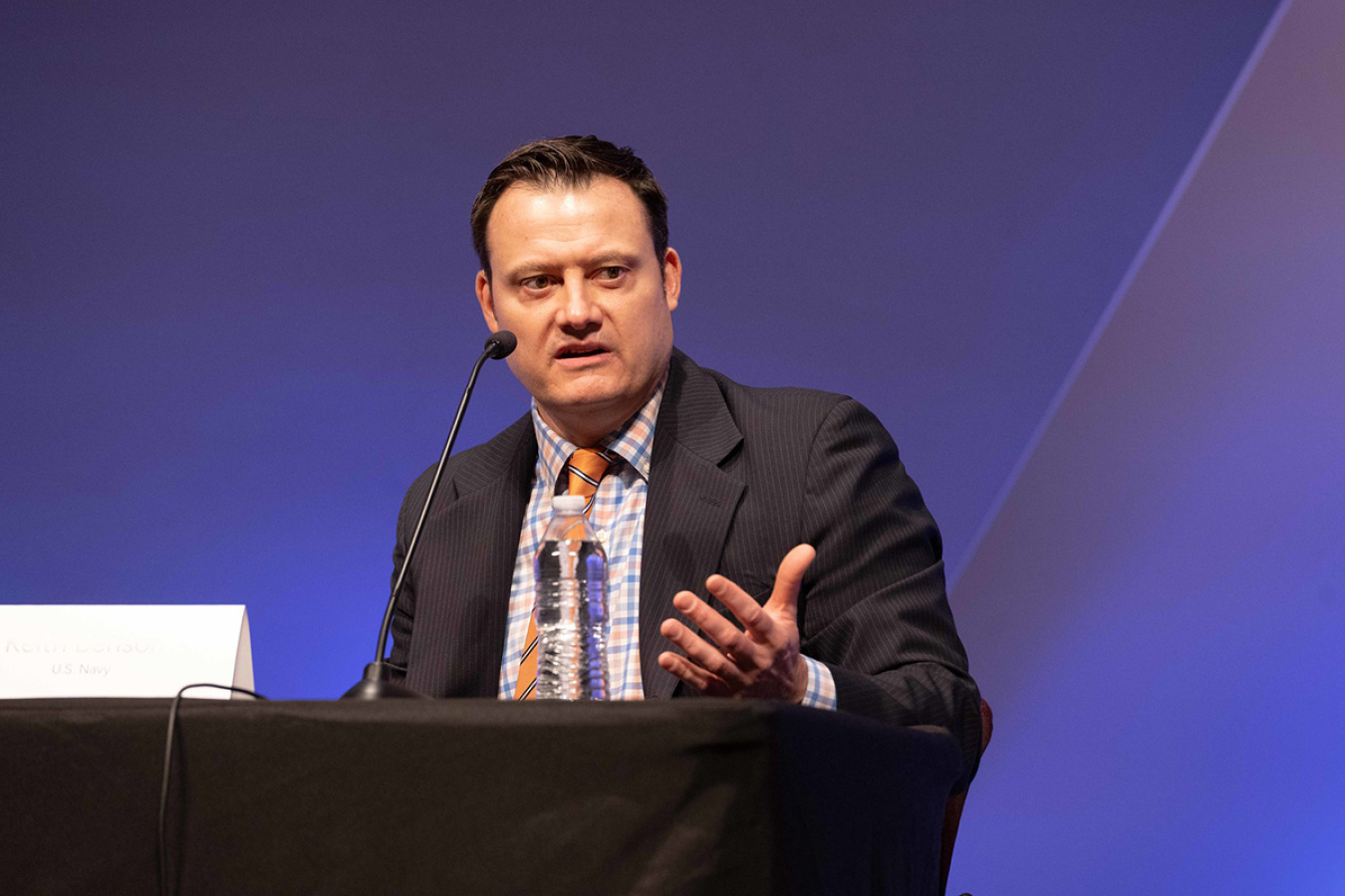 An individual sitting at a table participating in a panel discussion.
