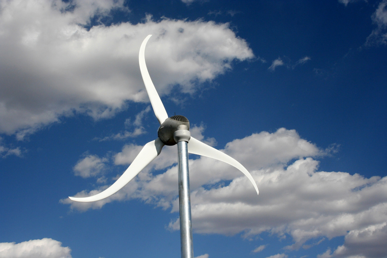 A small wind turbine against a cloudy blue sky