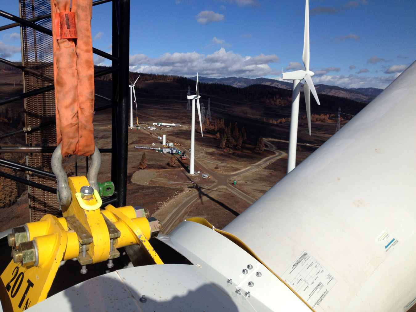 A crane lifting parts in front of a row of wind turbines