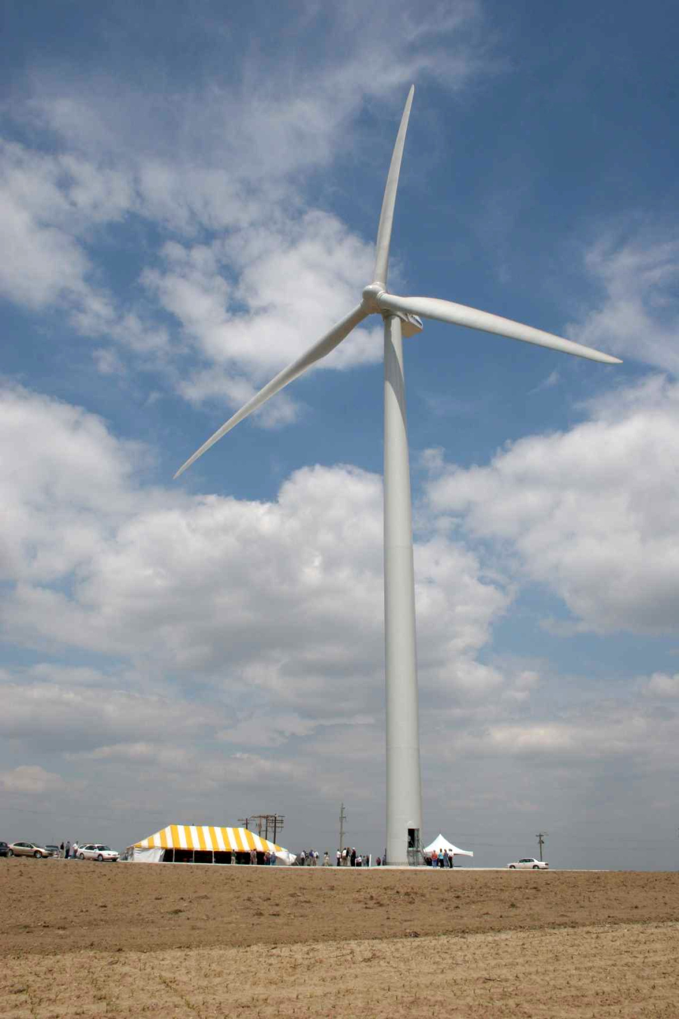 Cars and tents beneath a wind turbine