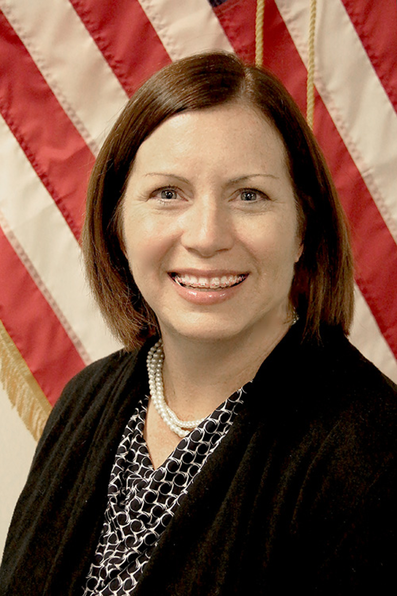 Professional headshot of a woman in front of the American flag