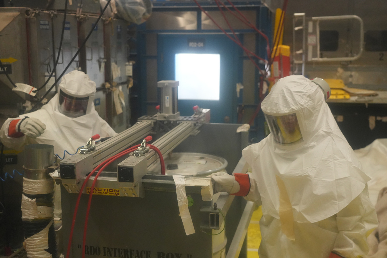 Employees in hazmat suits working on processing waste