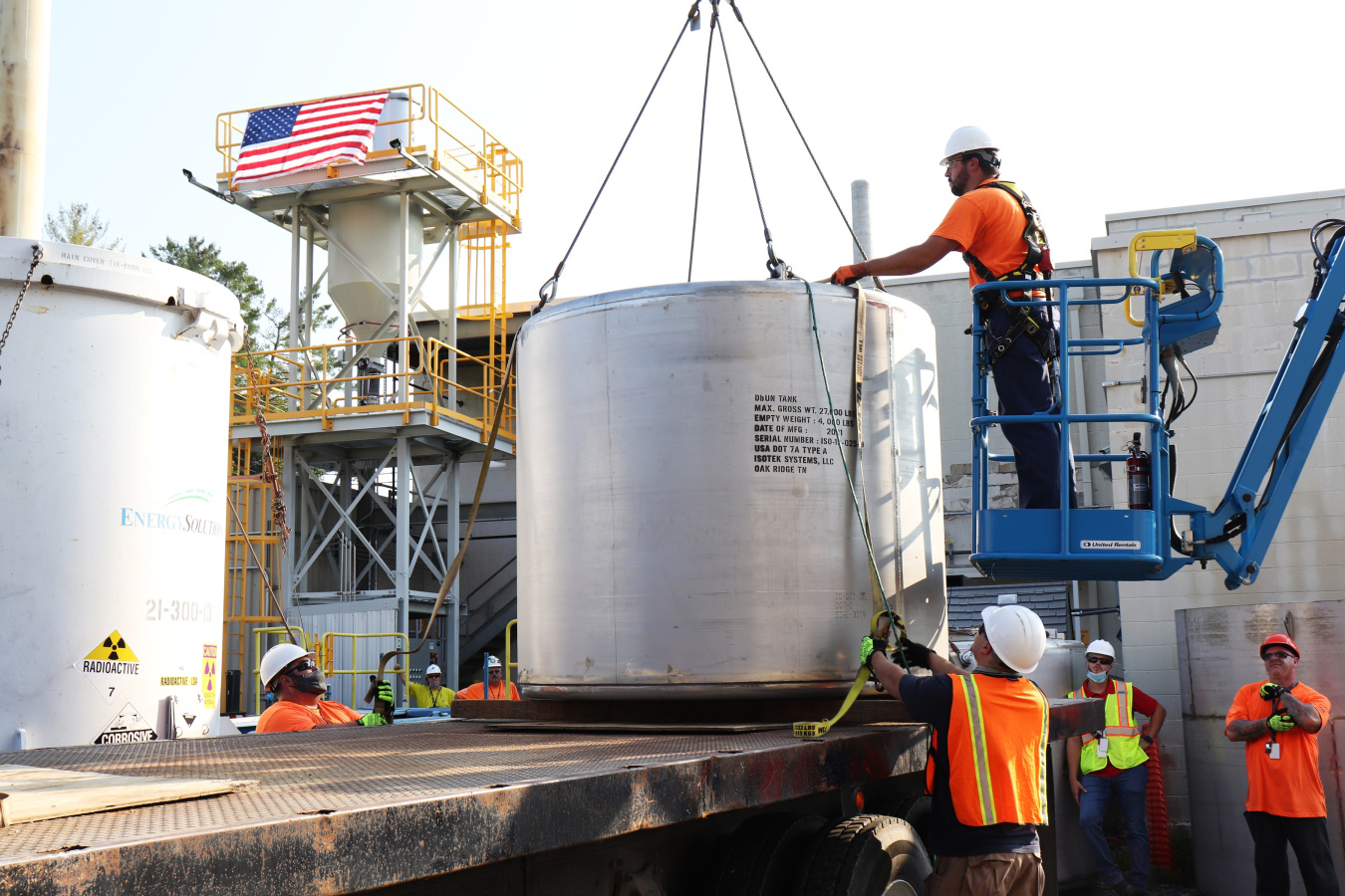 Employees loading a large waste container onto a truck for shipment