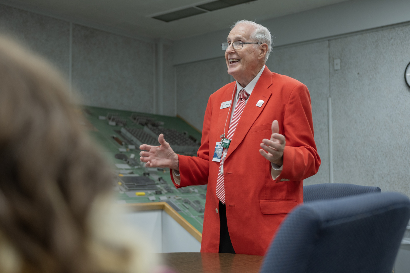 A man in an orange suit giving a tour to a group of people