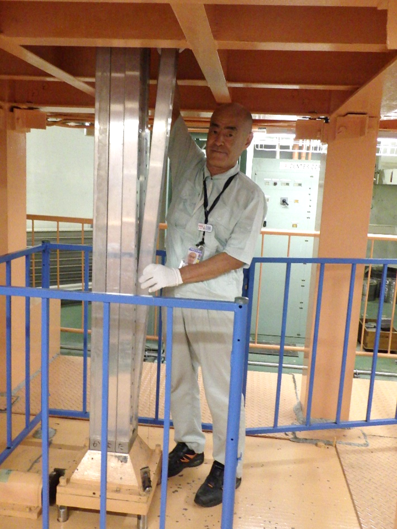 A man holds onto a tall, metal column in a cordoned-off area.