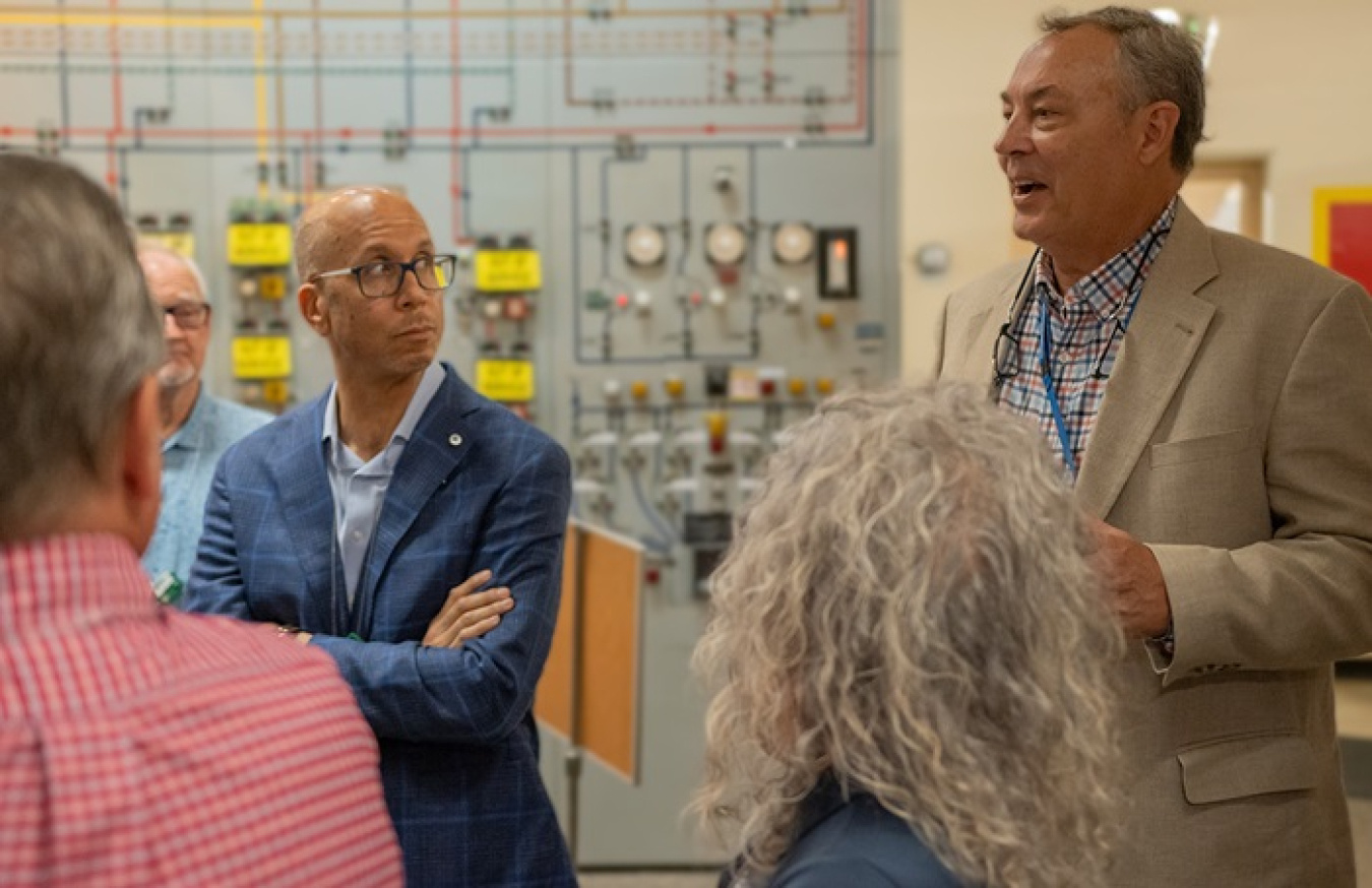 A man in a brown suit speaking to a group of people