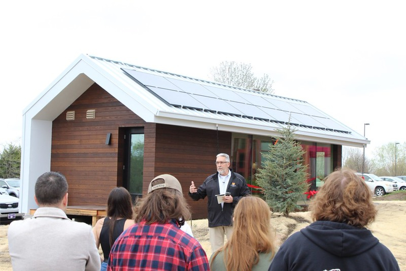 This team's house in the background, with a few people standing in the foreground, backs to the camera.