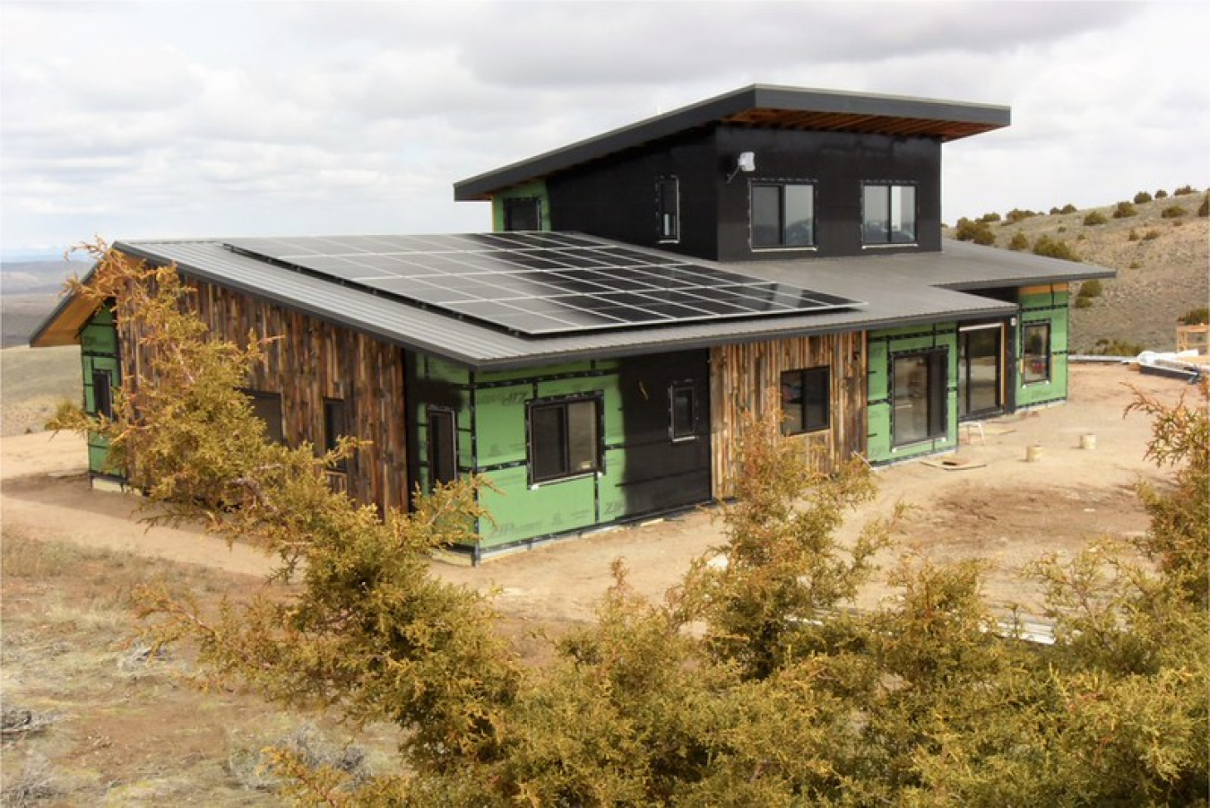 Exterior of the team's house, in a dry, desert-like setting with some trees / shrubs in the foreground.