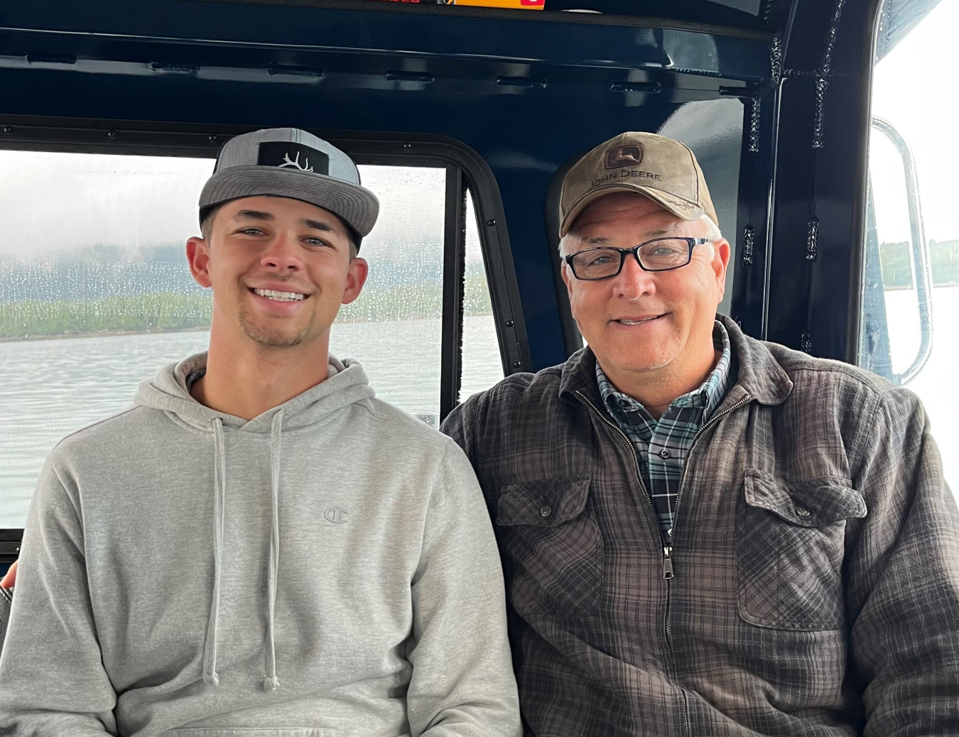 A young man and an older man sitting beside each other inside a vehicle 
