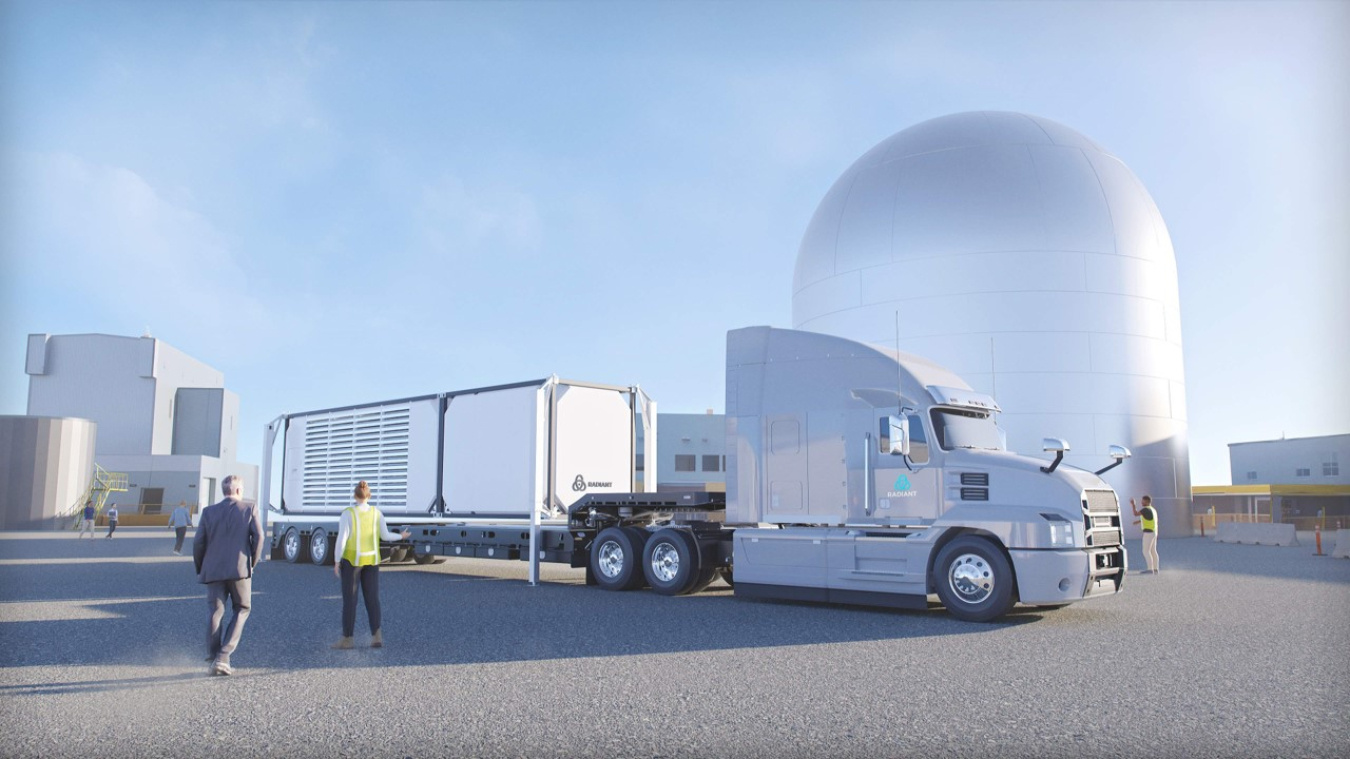 A semi truck carrying a microreactor sits in front of a silver dome-shaped building.