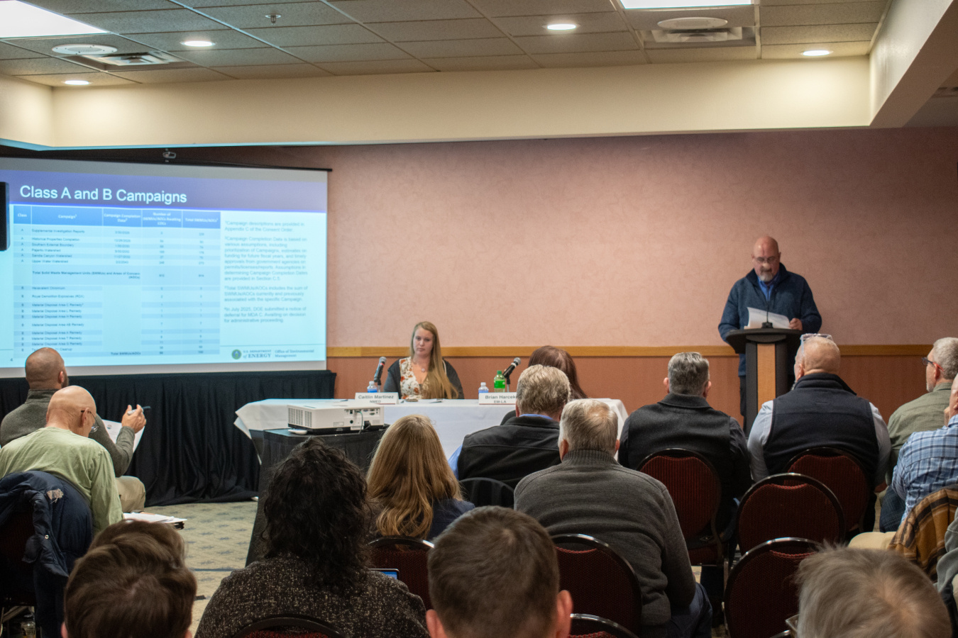 A panel at the front of a room with a presentation for a crowd