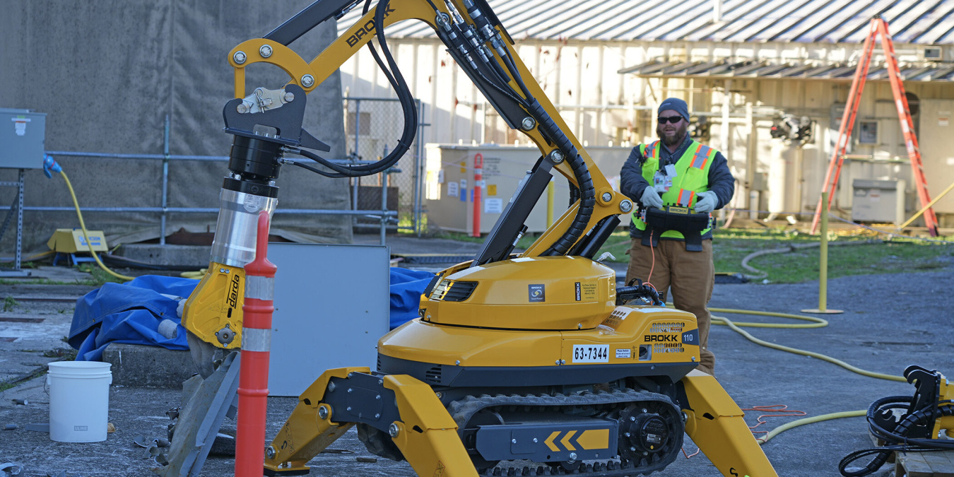 An employee using a large yellow machine with a robotic arm