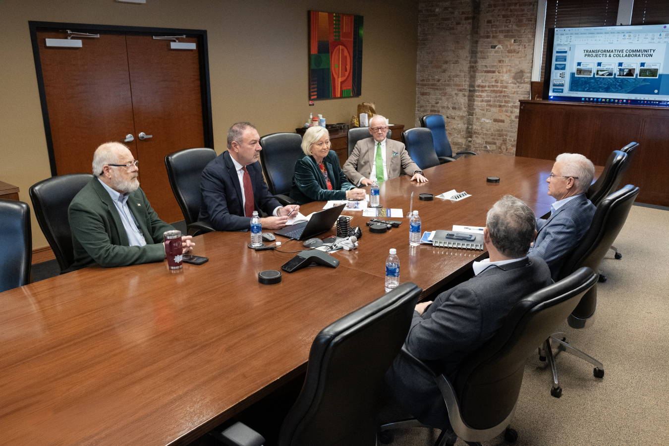 Six professionals sitting at a conference table having a discussion