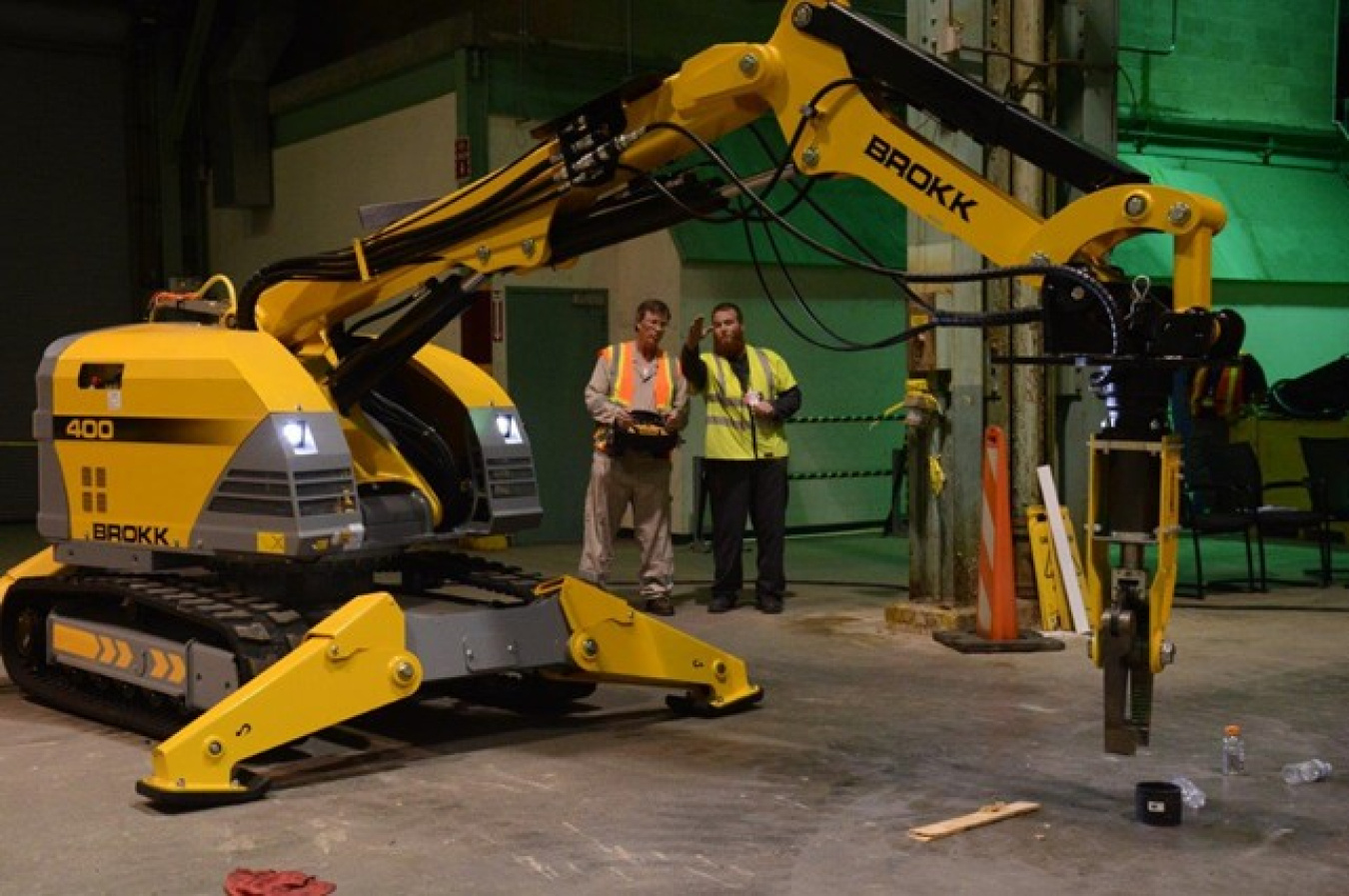 Two employees operating a large yellow machine with a robotic arm