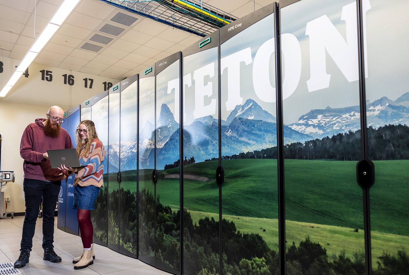 Researchers stand next to a server rack with "TETON" printed over a mountain scene.